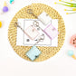 Four blank mini photo album keychains arranged on a woven straw mat