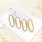 Four blank pearl edged gold metal hair clips on a magazine page