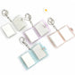 Four blank photo album keychains opened flat, showing the hinged white sleeves