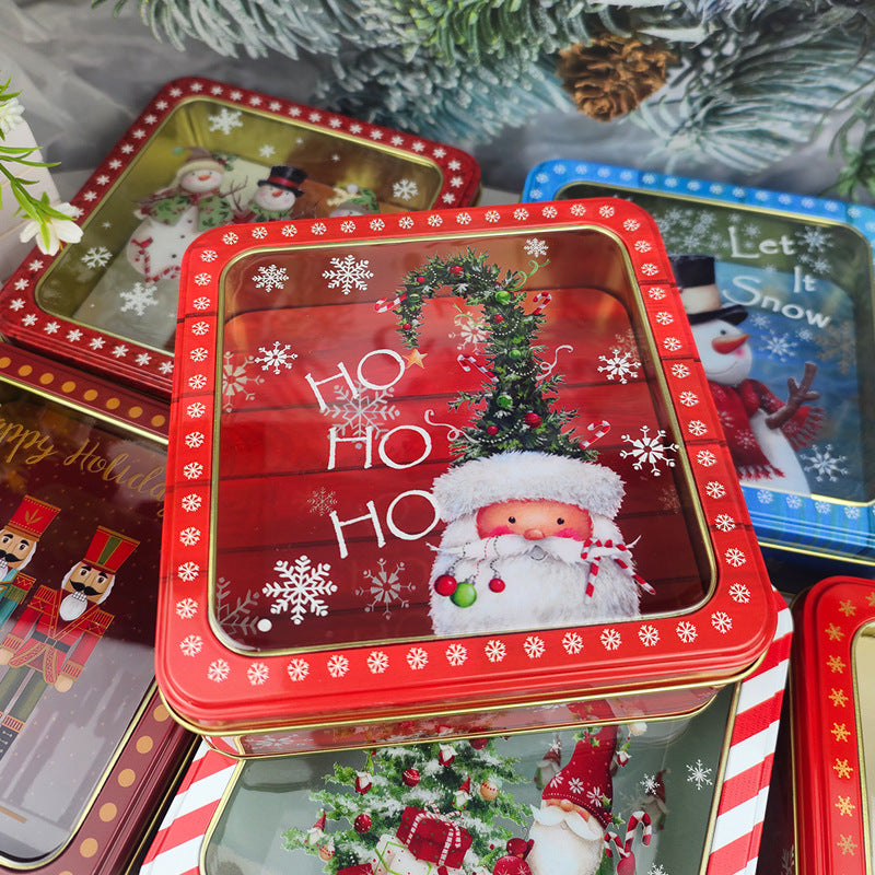 Red Christmas tin boxes with clear window lids stacked among pine branches