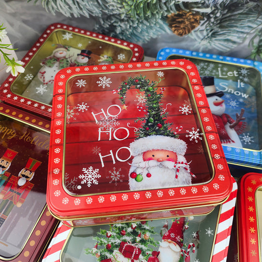 Red Christmas tin boxes with clear window lids stacked among pine branches